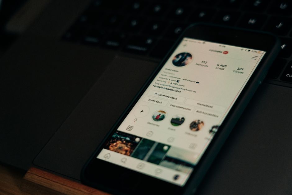 Smartphone mostrando un perfil de red social junto a una laptop